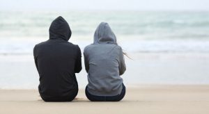 two sad people sitting at the beach